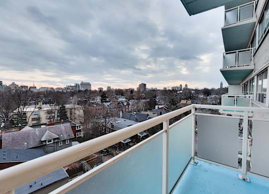 A balcony overlooks a residential area with houses and trees.