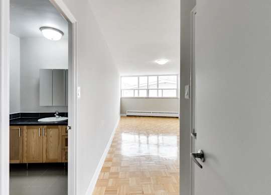 an open door leading to a bathroom with a sink and a mirror