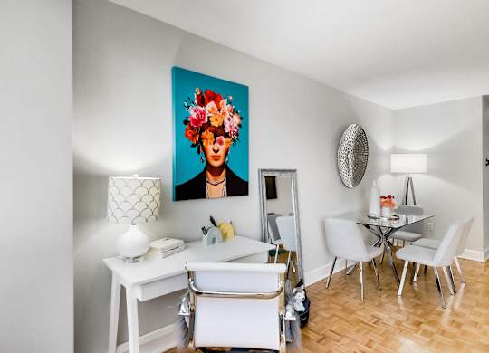 A dining room with a white table and chairs and a painting of a woman with flowers in her hair.