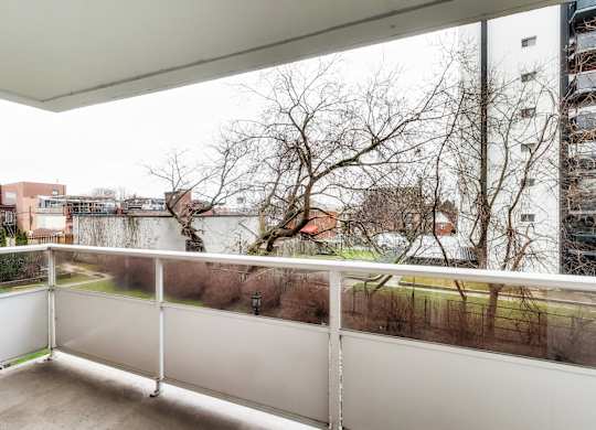 A balcony with a white railing overlooks a residential area.
