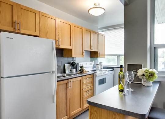 a kitchen with wood cabinets and white appliances and a counter top with a white refrigerator