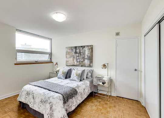 A bedroom with a bed, nightstand, and a painting on the wall.