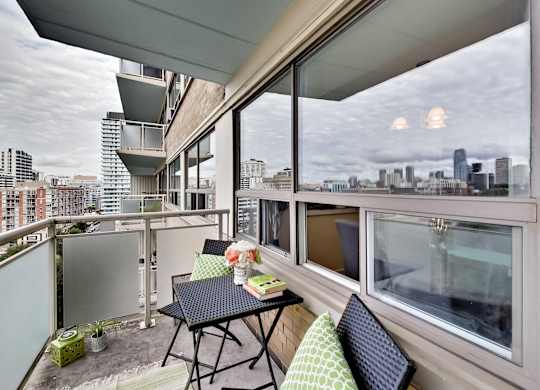A balcony with a table and chairs overlooking a city skyline.
