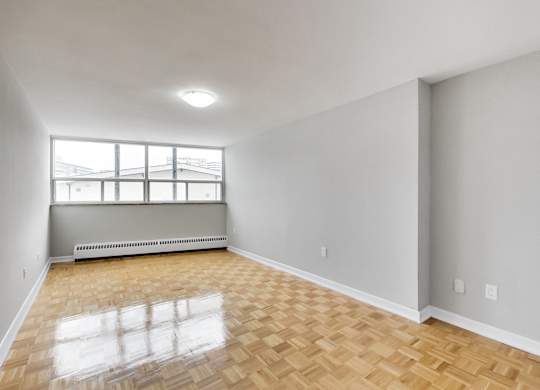 an empty living room with wood flooring and a window