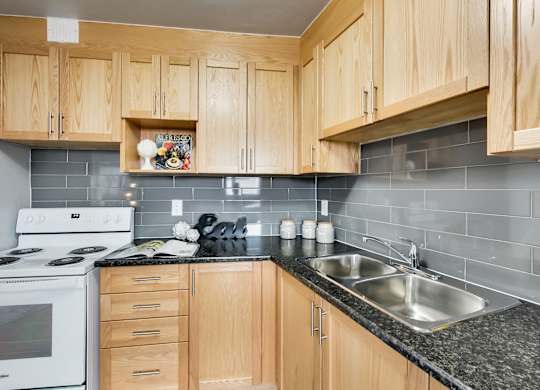 the kitchen has granite counter tops and white appliances and wood cabinets