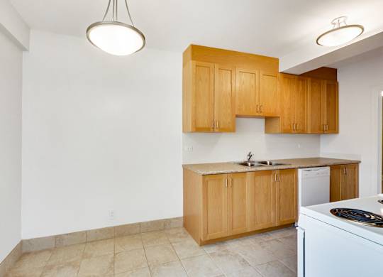 an empty kitchen with white appliances and wooden cabinets