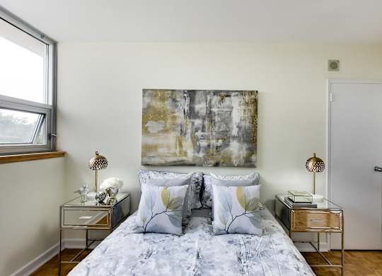 A bedroom with a large bed and a painting on the wall.