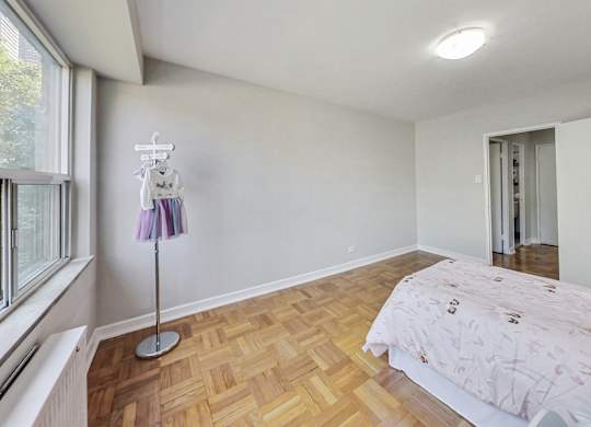 a bedroom with wood flooring and a bed and a window