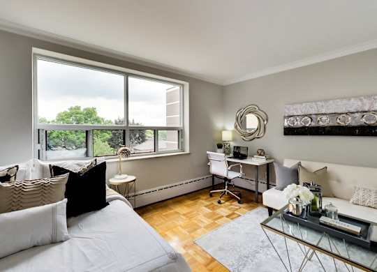 a living room with a couch and a desk and a window