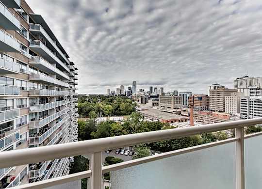 A view of a city from a balcony with a cloudy sky.