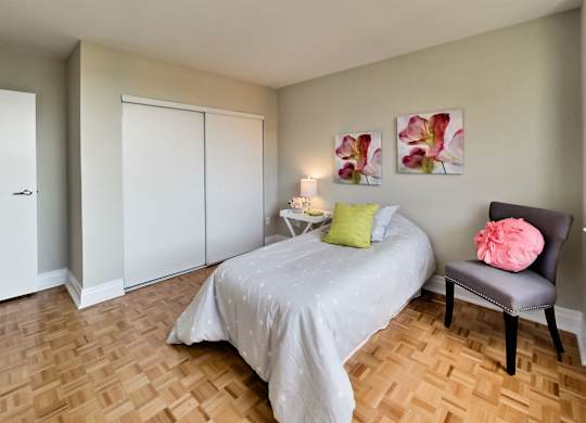 a bedroom with a bed and a chair and a wood floor