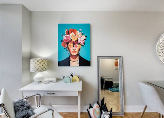 A room with a white desk and a painting of a woman with flowers in her hair.