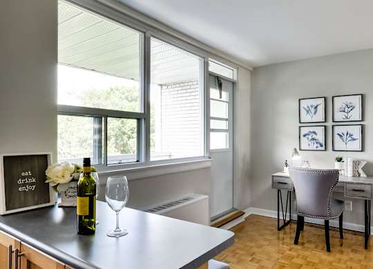 a dining room with a table and a desk with a chair and a wine glass