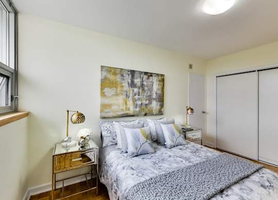 A bedroom with a bed, nightstand, and a painting on the wall.