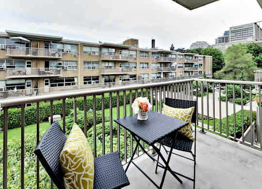 a balcony with a table and chairs and a view of an apartment building