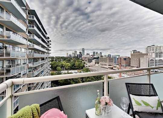 A balcony with a table set for two overlooks a cityscape.