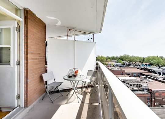 A balcony with a table and chairs overlooking a cityscape.