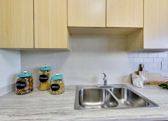 a kitchen counter with a sink and some jars on it