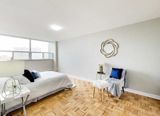 a bedroom with a bed and a chair and a window