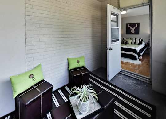 A room with a white brick wall and a bed with a black and white striped comforter.
