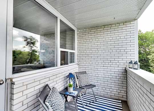 a balcony with two chairs and a table and a window