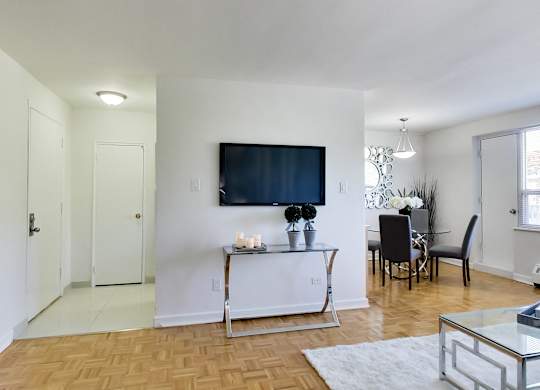 a living room with a tv on the wall and a dining room table