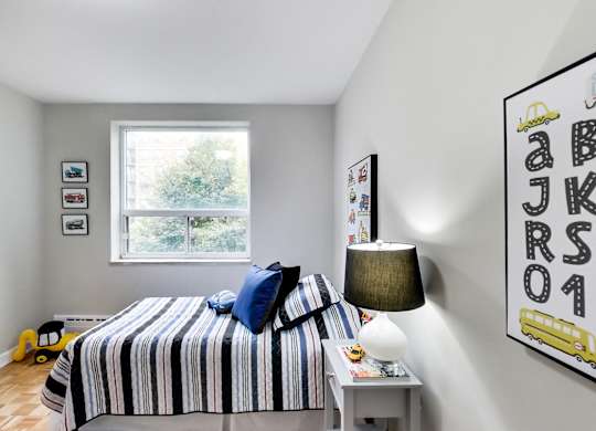 a bedroom with a bed with a striped blanket and a window