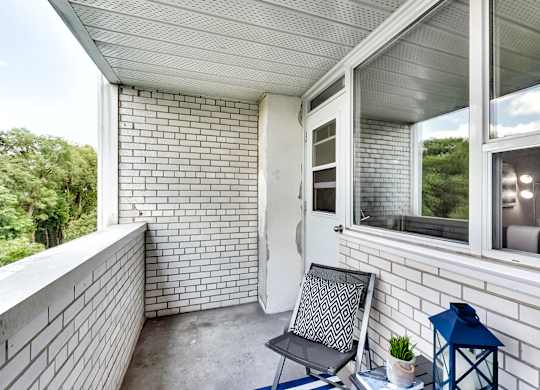 a balcony with a chair and a table and a window