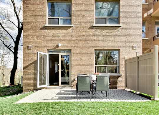 a patio with a table and chairs in front of a brick house