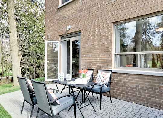 a patio with a table and chairs in front of a brick house