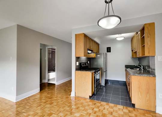 an empty kitchen with wooden cabinets and a stainless steel refrigerator