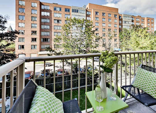 a balcony with chairs and a table and a view of a building