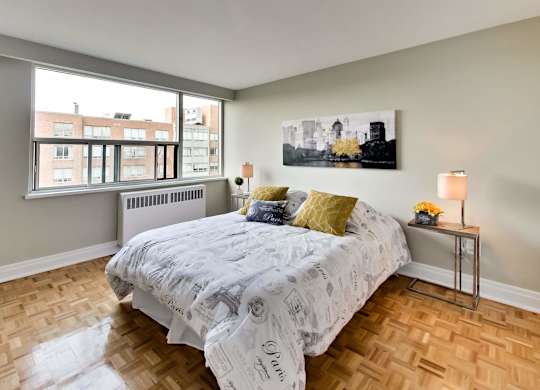 a bedroom with a bed and a large window and wooden floors