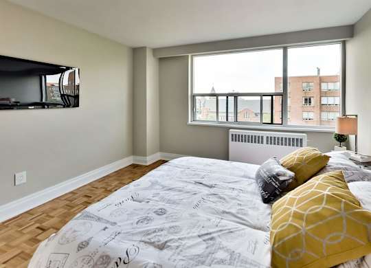 a bedroom with a large window and a bed with yellow pillows