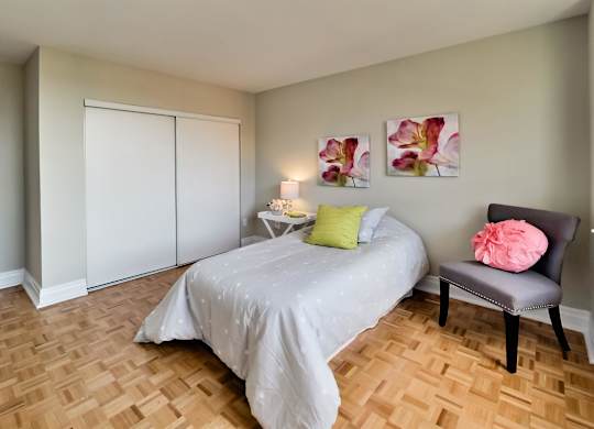a bedroom with a bed and a chair and a wood floor