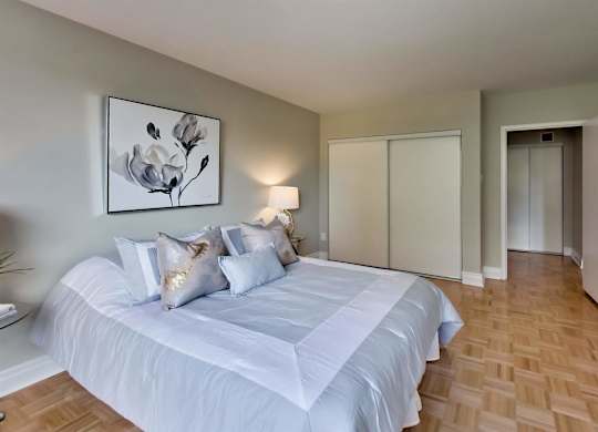 a bedroom with a white bed and a painting on the wall