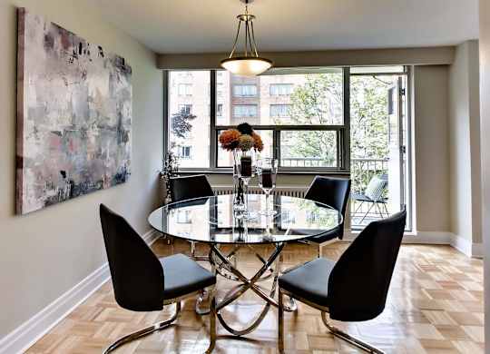 a dining room with a glass table and chairs and a large painting