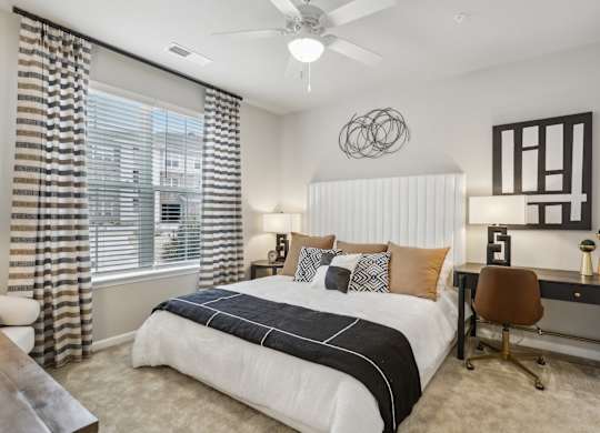 a large bedroom with a ceiling fan and large window