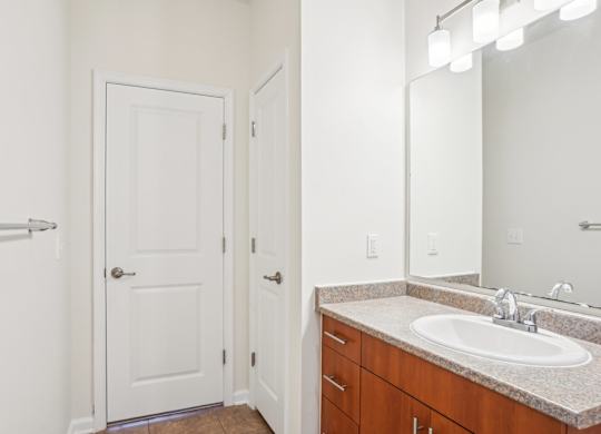 A bathroom with a sink, mirror, and a white door.