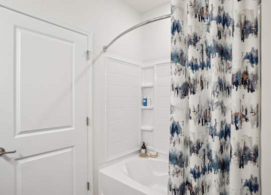 A white bathroom with a blue and white shower curtain.
