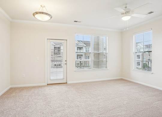 A room with a carpeted floor and a ceiling fan.
