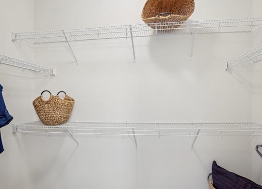 A white wall with three shelves and a basket on the top shelf.