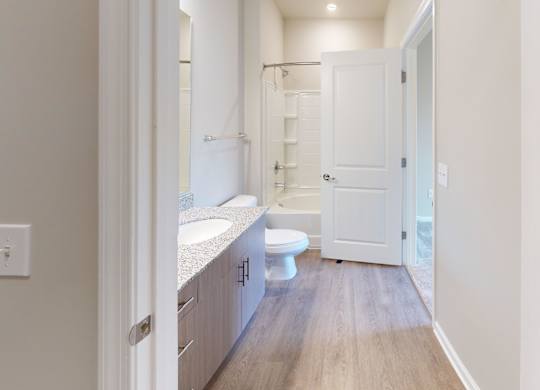 a connecting bathroom with luxury vinyl flooring and granite countertops