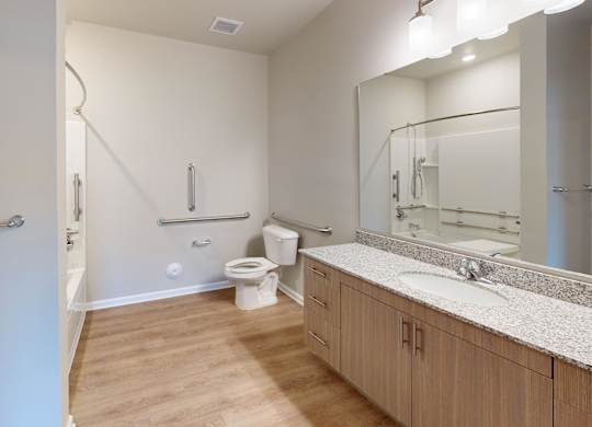 a bathroom with luxury vinyl flooring and handrails