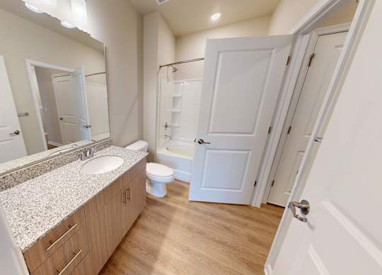 a bathroom with granite countertops and luxury vinyl flooring