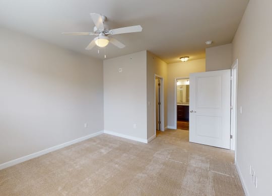 Bedroom with ceiling fan, carpet and door to bathroom