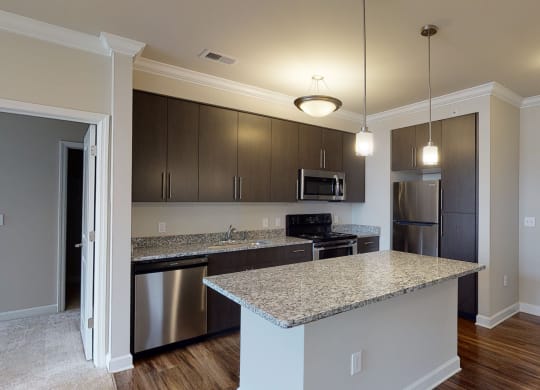 Kitchen with island, dark cabinets, vinyl floors and granite countertops