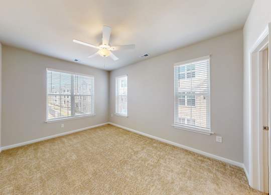 a spacious bedroom with a ceiling fan and windows