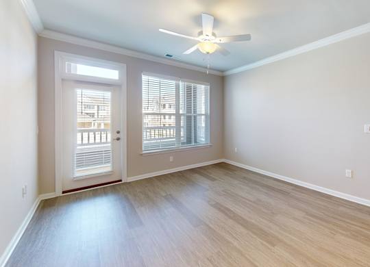 a spacious living room with a ceiling fan and private patio access