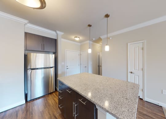 Kitchen with island, dark cabinets, vinyl floors and granite countertops